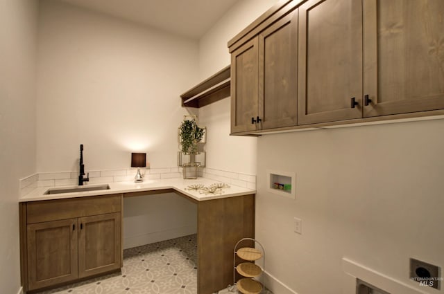 clothes washing area with cabinets, sink, and washer hookup