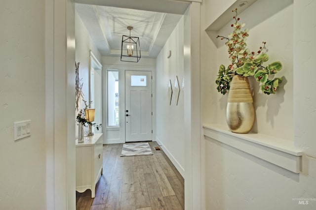 entrance foyer featuring hardwood / wood-style flooring, a raised ceiling, and a notable chandelier