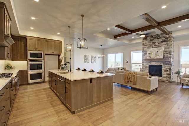 kitchen featuring sink, a large island with sink, hanging light fixtures, light hardwood / wood-style floors, and stainless steel appliances