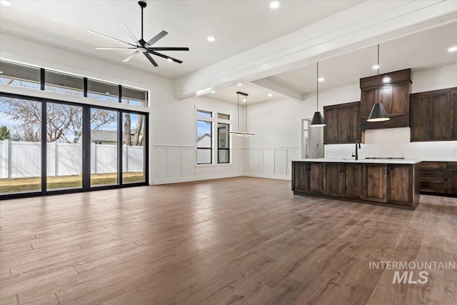 kitchen featuring light countertops, light wood-style floors, open floor plan, ceiling fan, and dark brown cabinets