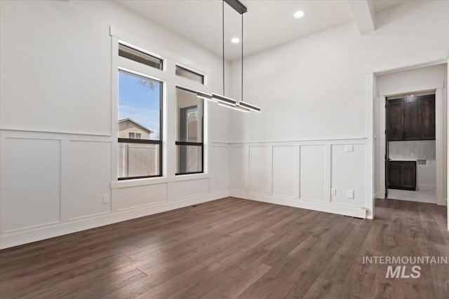 unfurnished dining area featuring dark wood-type flooring, recessed lighting, a decorative wall, and beamed ceiling