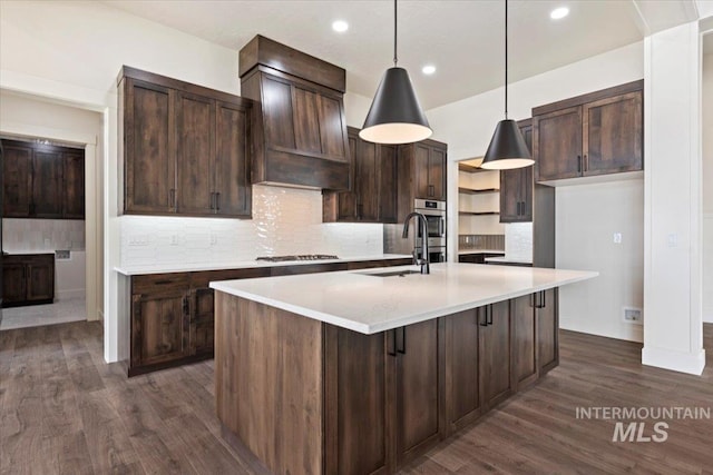 kitchen with dark wood finished floors, stainless steel gas cooktop, a sink, and dark brown cabinets