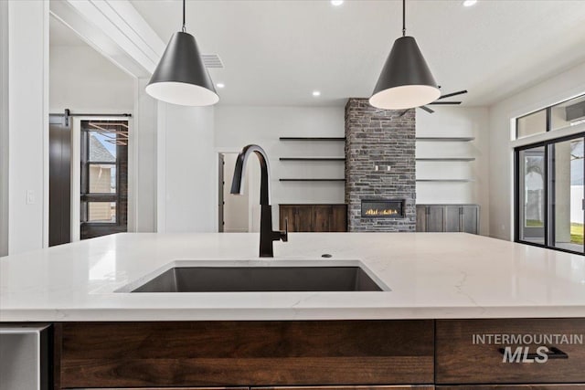 kitchen featuring plenty of natural light, open floor plan, a sink, and light stone countertops