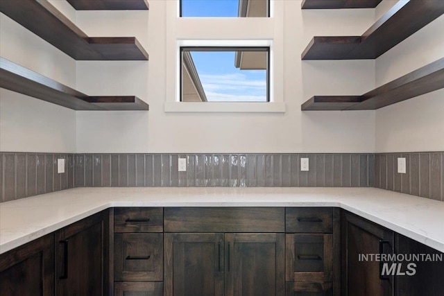 kitchen with light stone countertops, dark brown cabinets, and open shelves