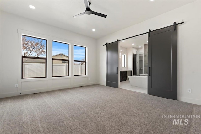 unfurnished bedroom featuring light carpet, a barn door, baseboards, and recessed lighting