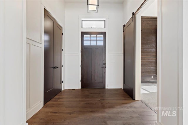 entryway featuring a wainscoted wall, a barn door, wood finished floors, and a decorative wall