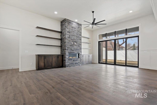 unfurnished living room featuring a stone fireplace, recessed lighting, wood finished floors, a ceiling fan, and built in features