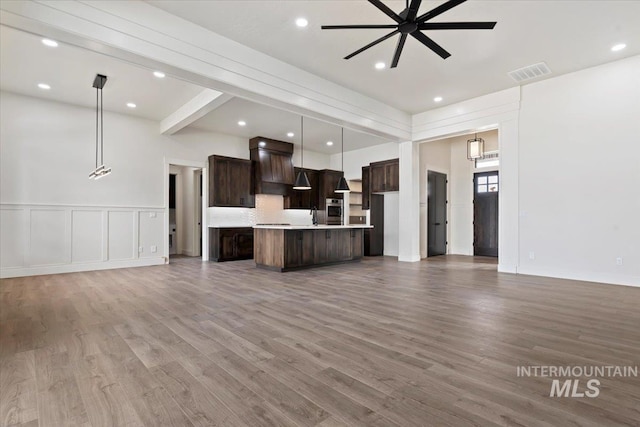 unfurnished living room with visible vents, a ceiling fan, wood finished floors, a decorative wall, and recessed lighting