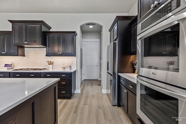 18279 N Tulip Ave, Nampa, ID 83687 - kitchen featuring appliances with stainless steel finishes, light countertops, arched walkways, light wood-style flooring, and decorative backsplash
