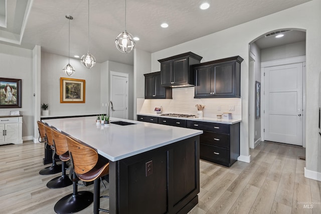 18279 N Tulip Ave, Nampa, ID 83687 - kitchen with decorative backsplash, arched walkways, light countertops, baseboards, and light wood finished floors