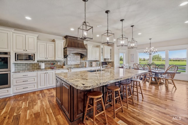 2466 Brooks Dr, Fruitland, ID 83619 - kitchen with appliances with stainless steel finishes, a sink, premium range hood, light wood-style flooring, and a kitchen breakfast bar