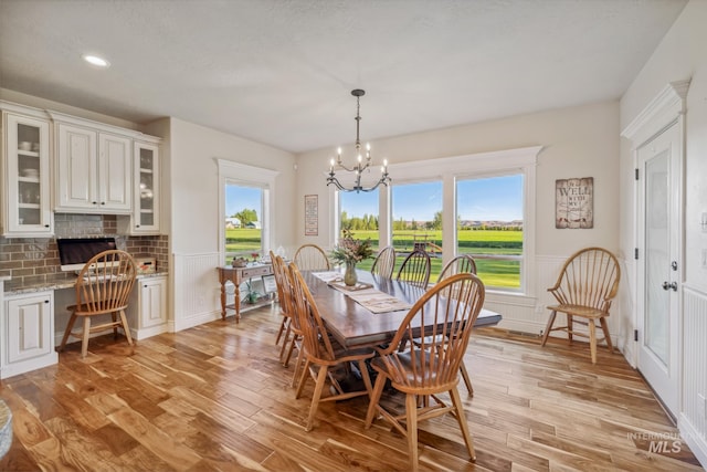 2466 Brooks Dr, Fruitland, ID 83619 - dining area with a chandelier, wainscoting, light wood finished floors, healthy amount of natural light, and a decorative wall