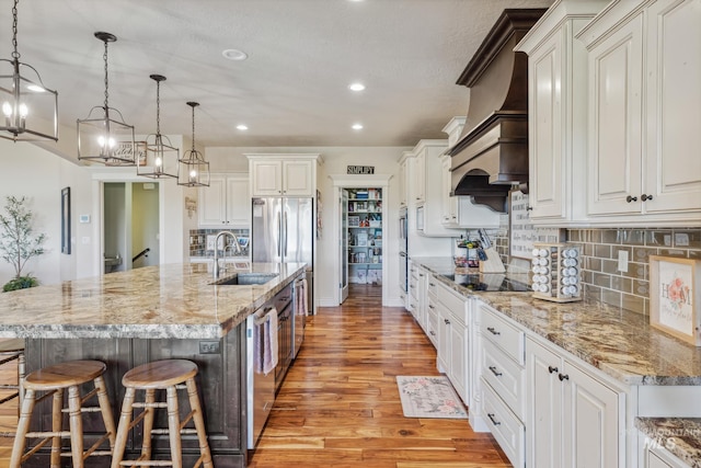 2466 Brooks Dr, Fruitland, ID 83619 - kitchen with a sink, light wood-style floors, black electric cooktop, recessed lighting, and a kitchen bar
