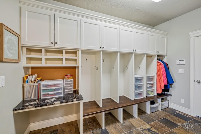 2466 Brooks Dr, Fruitland, ID 83619 - mudroom featuring dark stone finish flooring, baseboards, and a textured ceiling