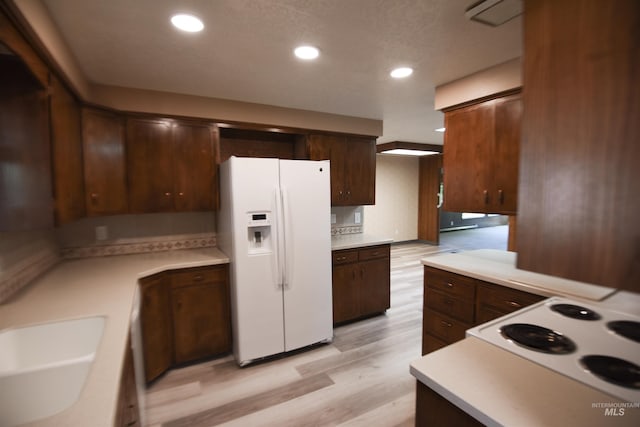 8395 W Golse Dr, Boise, ID 83704 - kitchen with dark brown cabinetry, white appliances, light countertops, and light wood-style floors