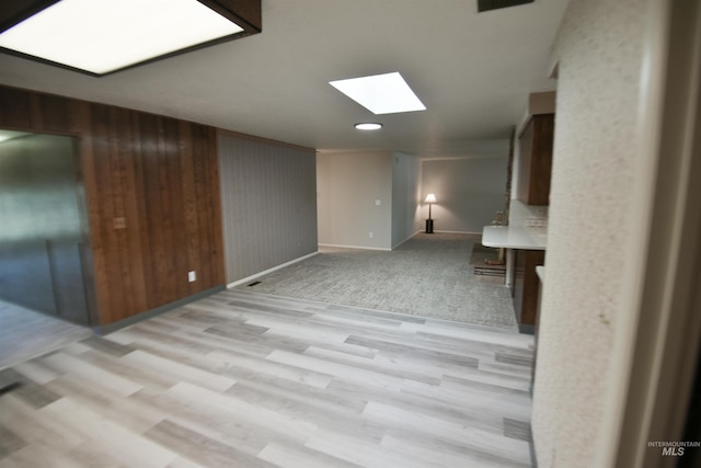8395 W Golse Dr, Boise, ID 83704 - unfurnished living room featuring baseboards, wooden walls, light wood-type flooring, and a skylight