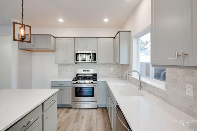 kitchen with gray cabinetry, stainless steel appliances, sink, and light hardwood / wood-style floors