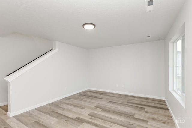 spare room with plenty of natural light, light wood-type flooring, visible vents, and baseboards