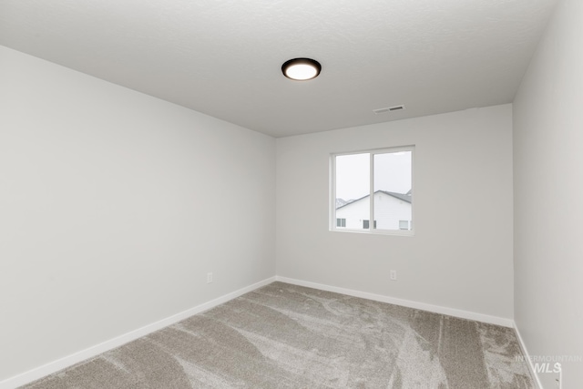 empty room with baseboards, a textured ceiling, visible vents, and carpet flooring