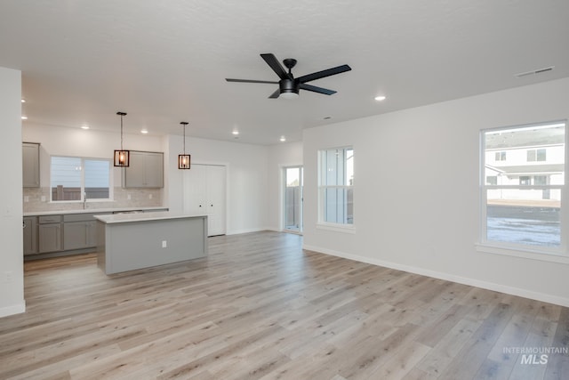 kitchen with a center island, pendant lighting, gray cabinets, and light hardwood / wood-style floors