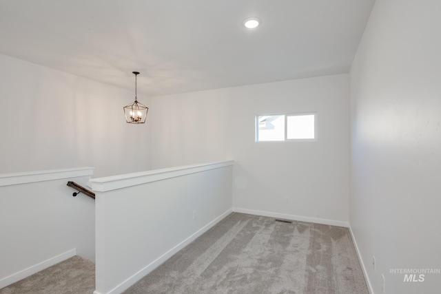 carpeted spare room featuring a chandelier