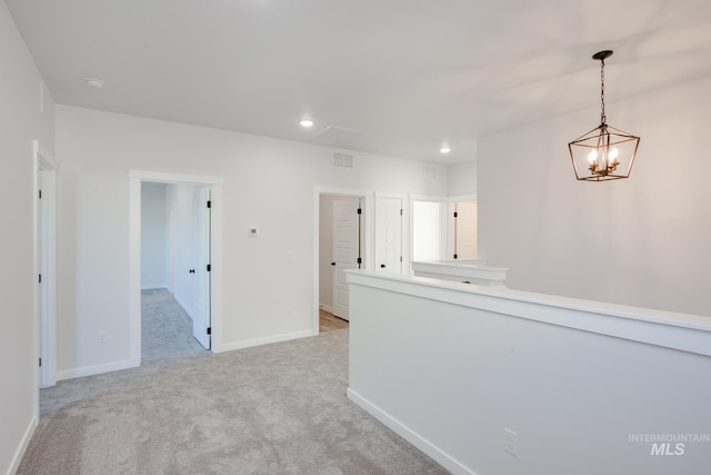 corridor with light colored carpet and a chandelier