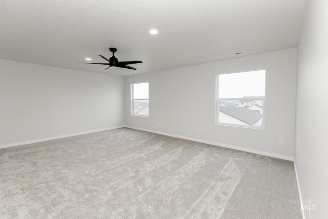 carpeted spare room featuring a textured ceiling, recessed lighting, a ceiling fan, and baseboards