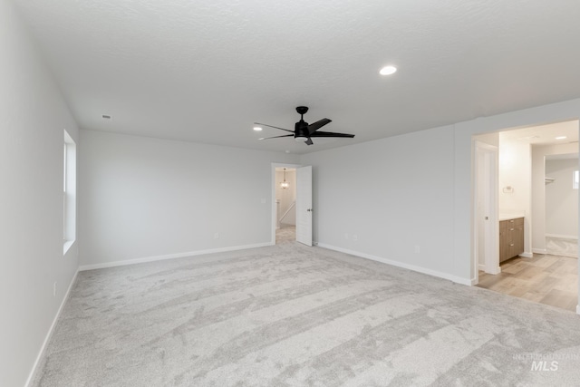 unfurnished room with recessed lighting, light carpet, a textured ceiling, and baseboards