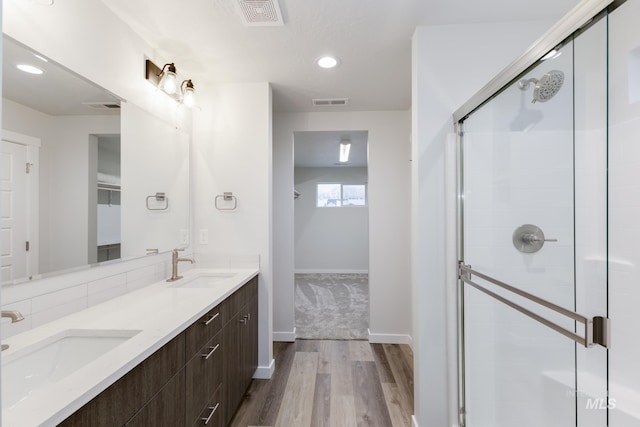 bathroom with a shower stall, visible vents, a sink, and wood finished floors