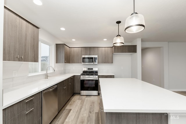 kitchen featuring appliances with stainless steel finishes, light wood-type flooring, a sink, and modern cabinets