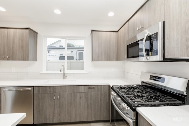 kitchen with stainless steel appliances, a sink, light countertops, and recessed lighting