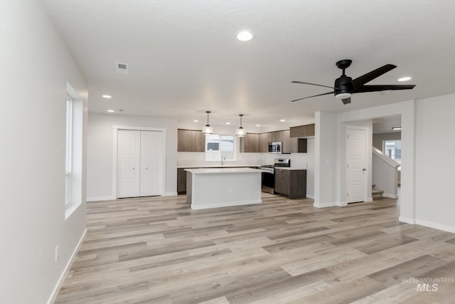 kitchen with stainless steel appliances, light countertops, visible vents, light wood-style flooring, and a kitchen island