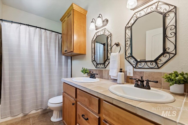 bathroom featuring double vanity, toilet, tile patterned floors, and a sink