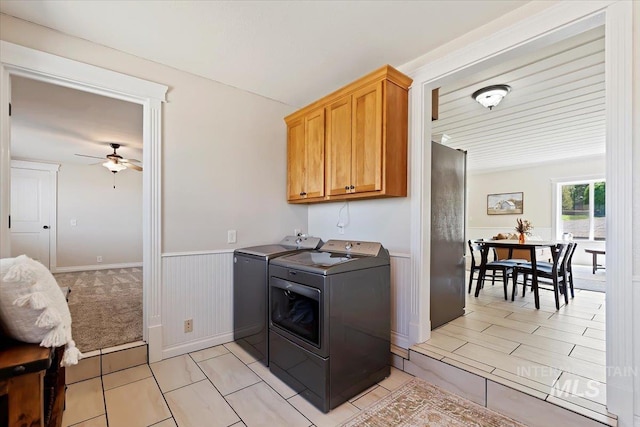 washroom featuring cabinet space, ceiling fan, wainscoting, and washer and dryer