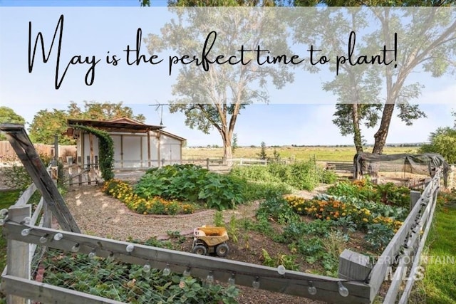 view of yard with a rural view, fence, and a vegetable garden