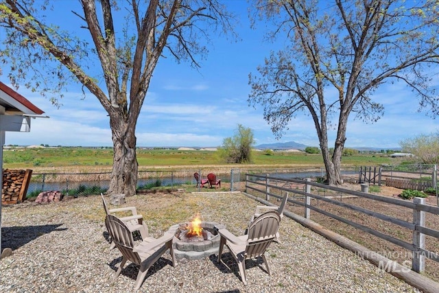 view of yard with fence, a water view, a fire pit, and a rural view