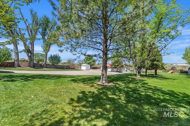 view of yard with an outbuilding, a playground, fence, and a storage shed