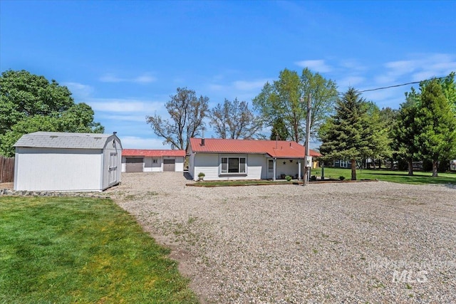 view of front of property featuring a storage shed, an outbuilding, metal roof, and a front yard