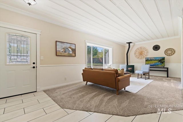 living area with crown molding, a wood stove, and a wainscoted wall