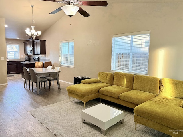 living room featuring light wood-type flooring, lofted ceiling, and ceiling fan with notable chandelier