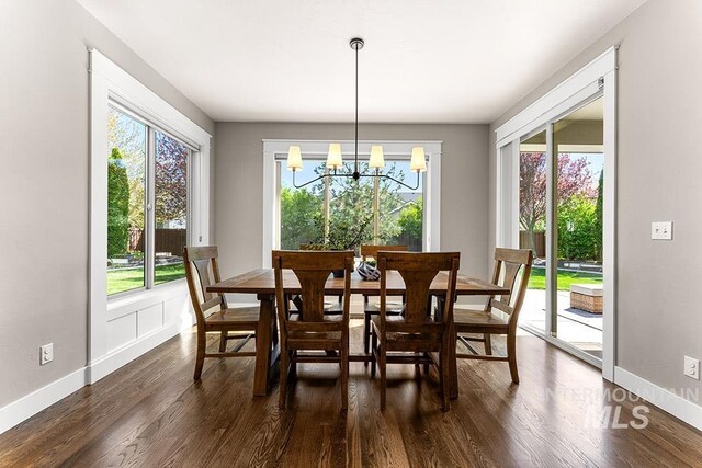 dining room with dark wood-type flooring, baseboards, and an inviting chandelier