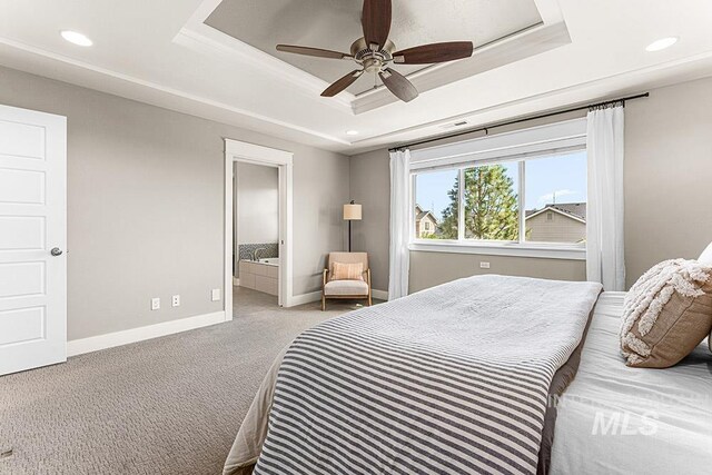 carpeted bedroom featuring baseboards, a tray ceiling, ensuite bathroom, and recessed lighting