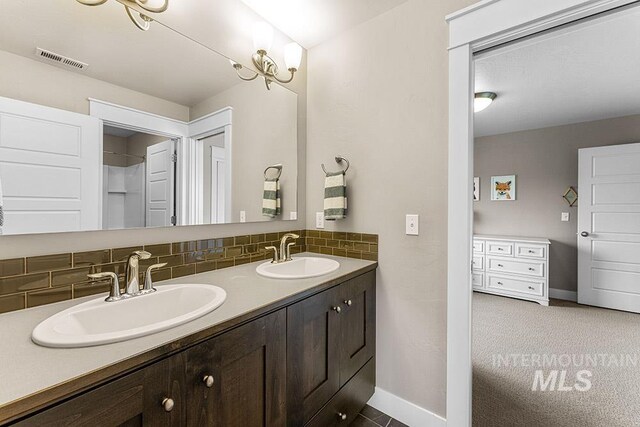 bathroom featuring decorative backsplash, visible vents, a sink, and double vanity