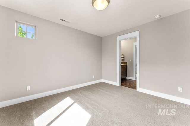 unfurnished room featuring baseboards, dark colored carpet, and visible vents
