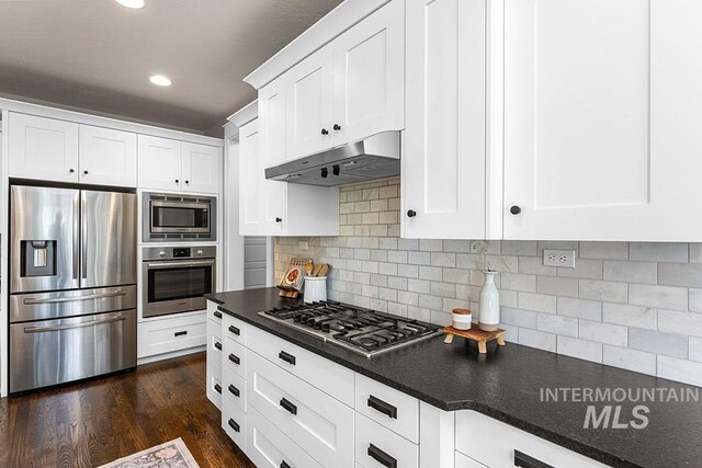 kitchen featuring under cabinet range hood, dark countertops, appliances with stainless steel finishes, and white cabinetry