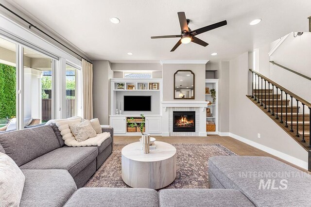 living area featuring baseboards, recessed lighting, a brick fireplace, stairway, and ceiling fan