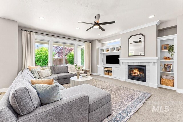 living room with recessed lighting, a ceiling fan, light carpet, baseboards, and a glass covered fireplace