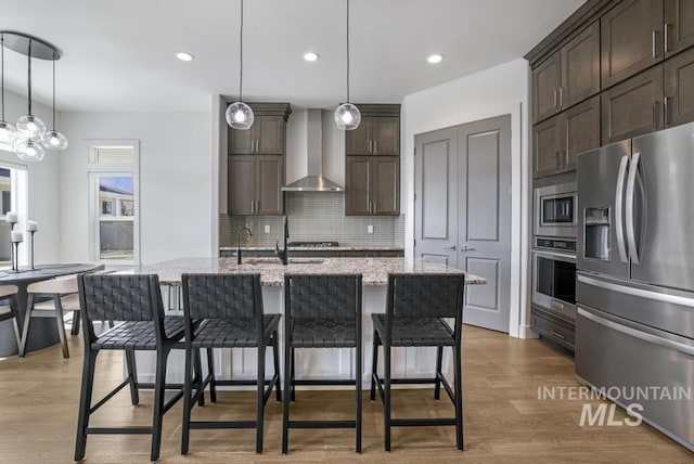 2252 Detweiler Pl, Twin Falls, ID 83301 - kitchen with decorative backsplash, a breakfast bar, wall chimney exhaust hood, stainless steel appliances, and dark brown cabinets