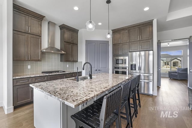 2252 Detweiler Pl, Twin Falls, ID 83301 - kitchen featuring a sink, wall chimney exhaust hood, tasteful backsplash, light wood-type flooring, and stainless steel appliances