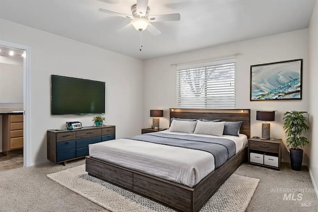 bedroom featuring ceiling fan, light colored carpet, and ensuite bath